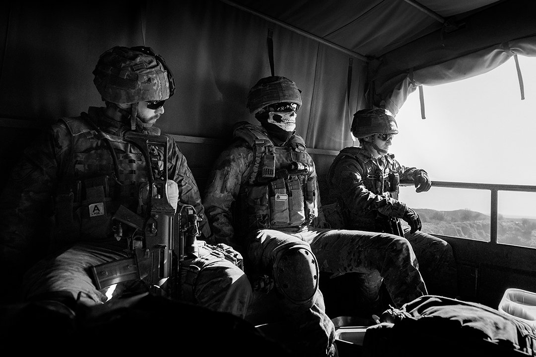 Service members in an interior beside a window.
